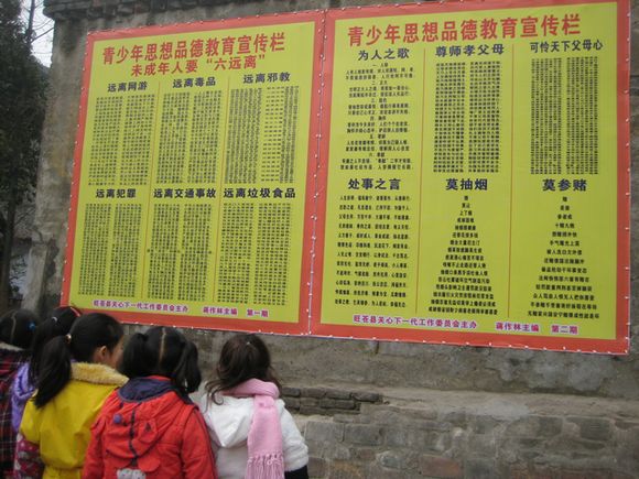 图为课间时分学生到宣传栏前仔细阅读，接受教育